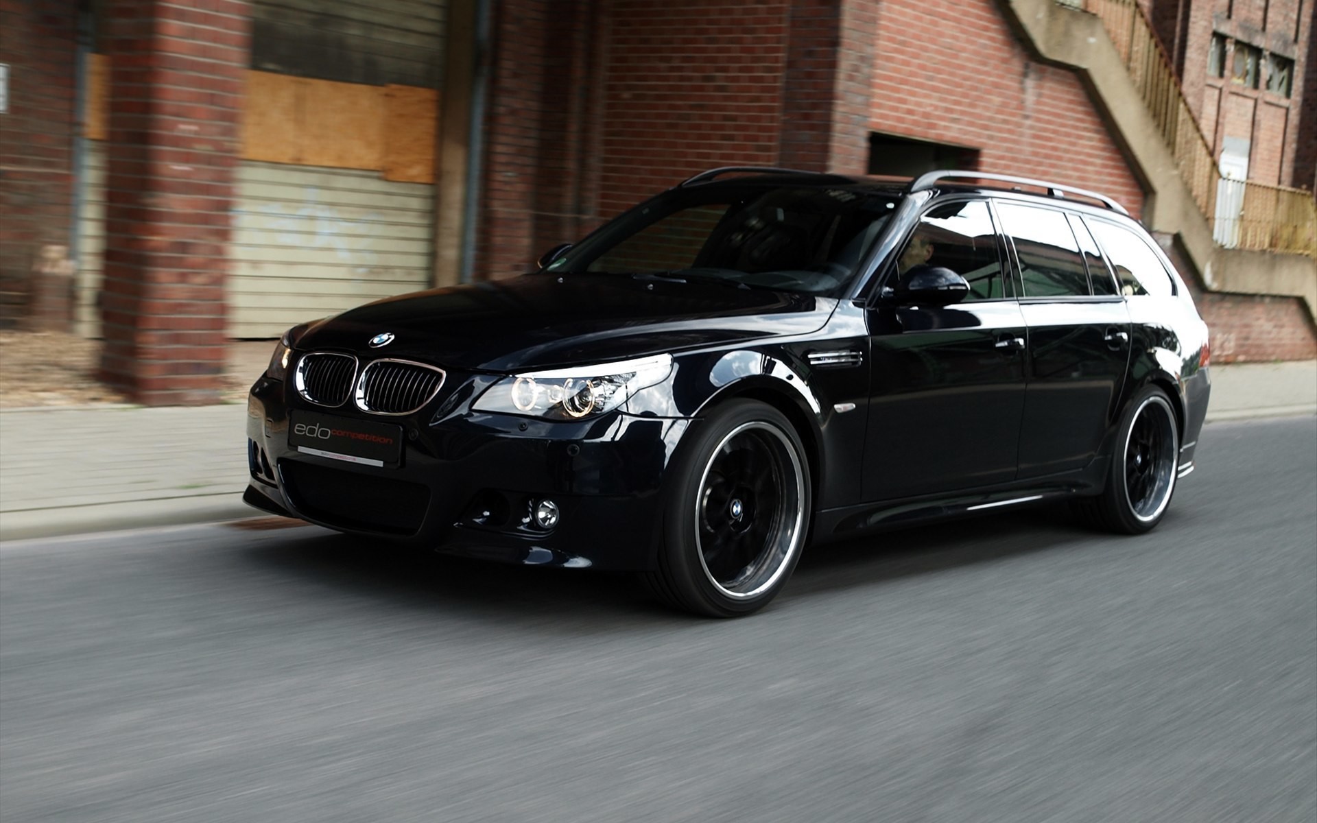 Glossy black BMW M5 Dark Edition on pavement in motion