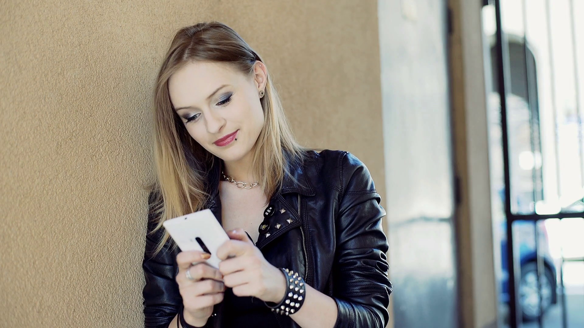 Punk girl texting on smartphone while leaning on the wall Stock Video Footage – VideoBlocks