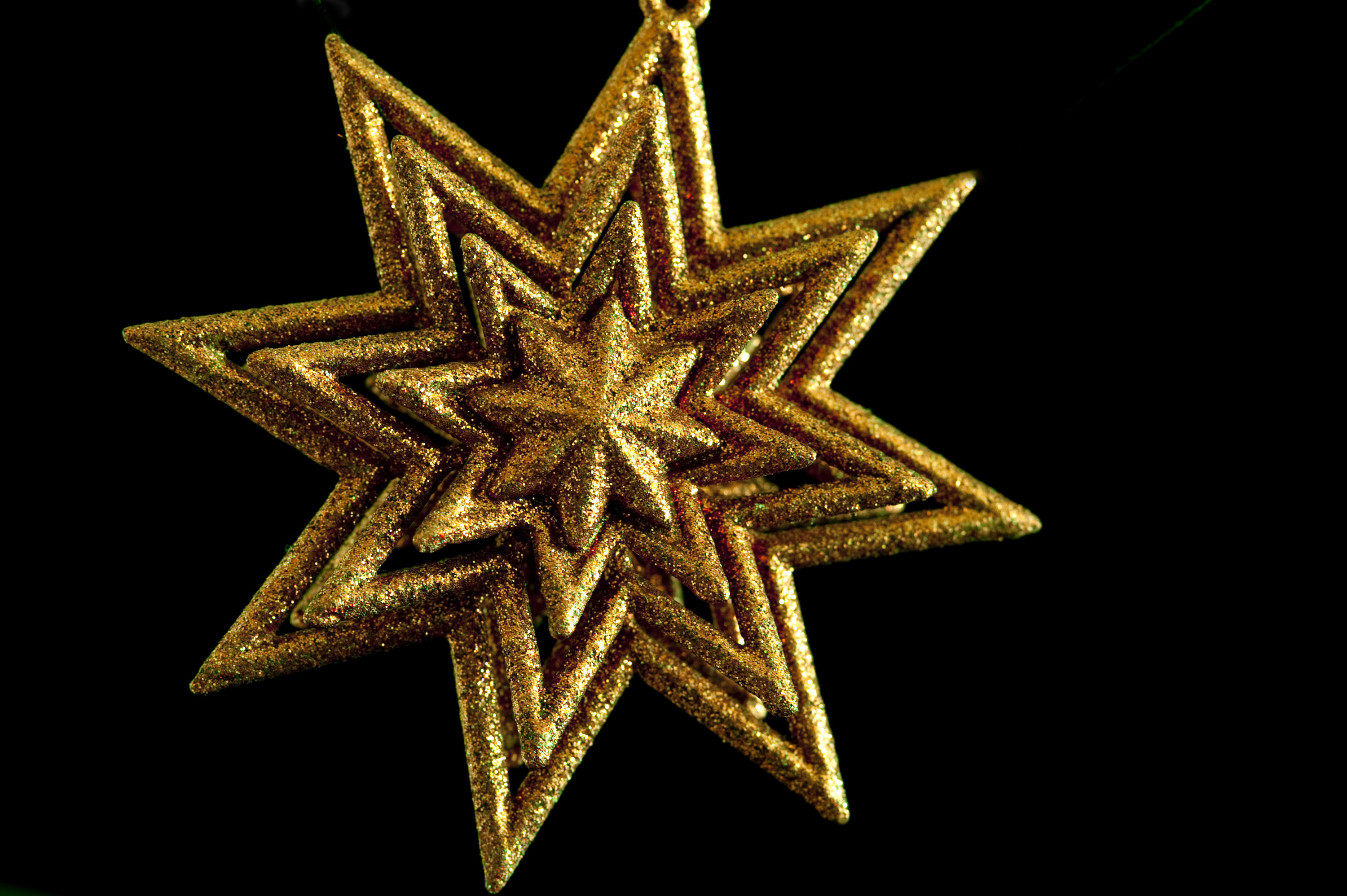 a gold coloured glittering christmas star on a black background