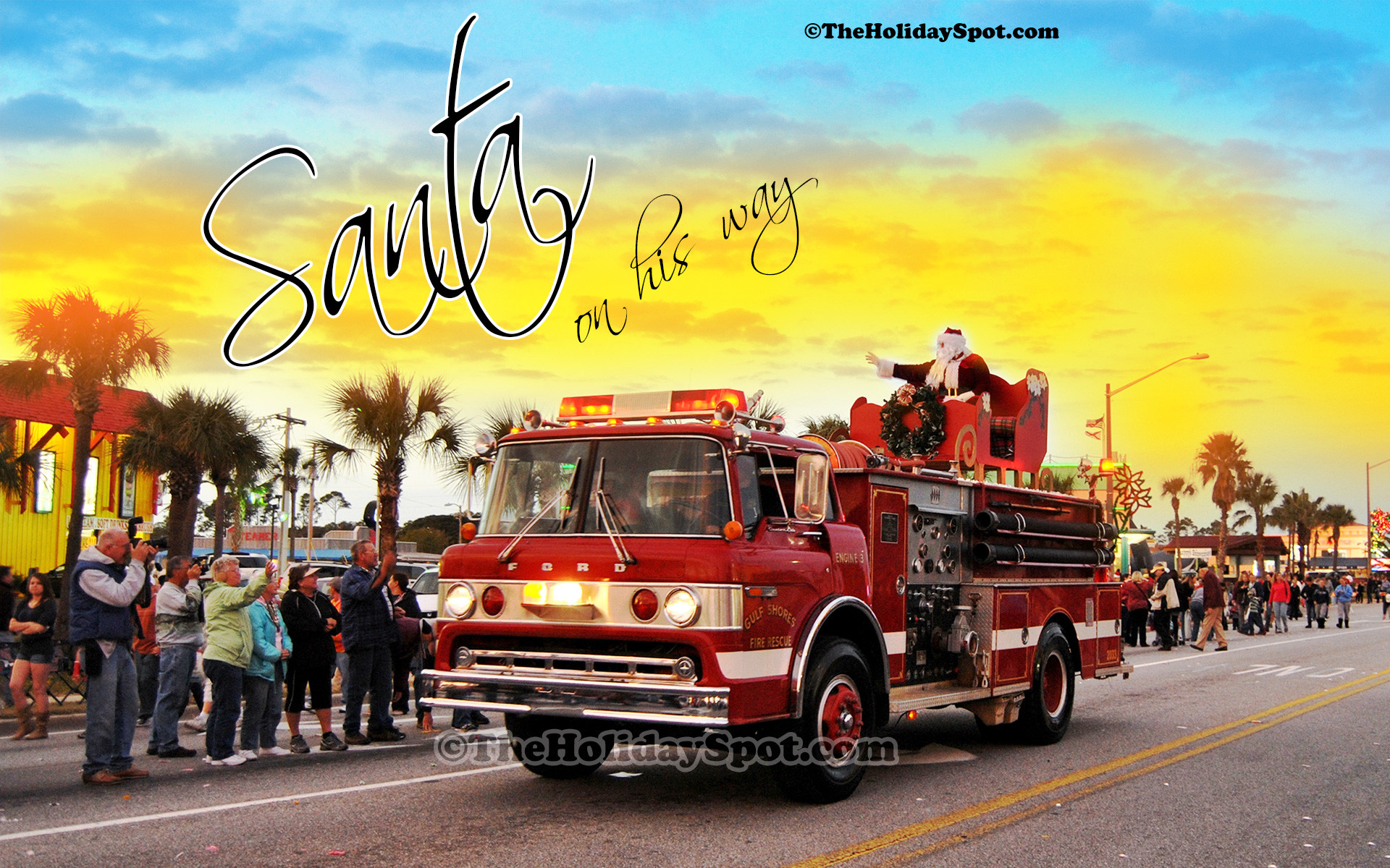 Christmas wallpaper of Santa coming to town on a firefighter truck.