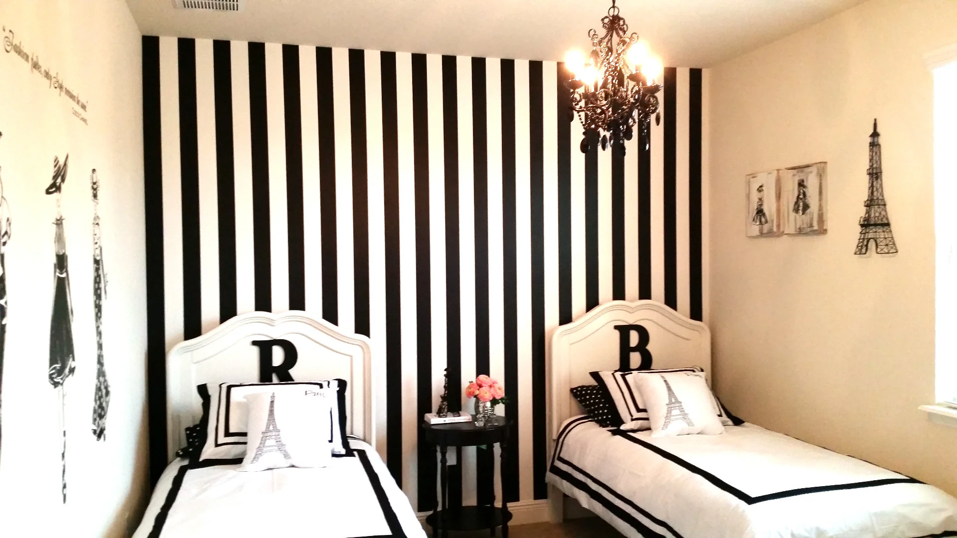 Double beds with Paris Themed Bedding before the white and black stripped wall plus black chandelier