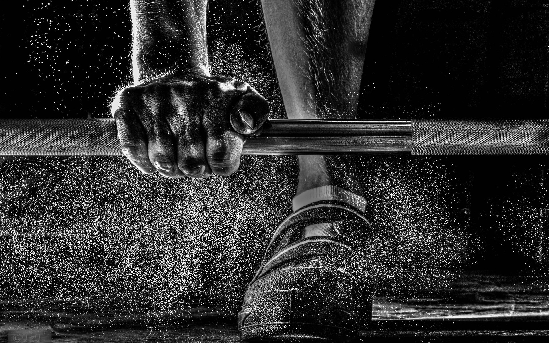 A Man Training Weight Lifting Barbell With Dust Flying Over His Shoes Black  And White